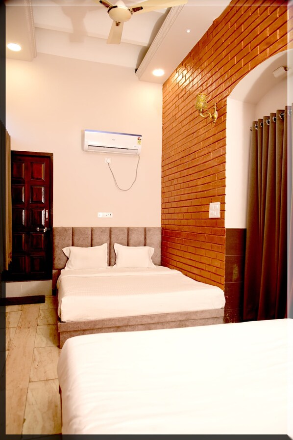 Une chambre d’hôtel avec un lit, un ventilateur de plafond, un appareil de climatisation, un mur en briques et une porte.