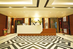 A reception area with a modern design, featuring a reception desk, a staircase, and decorative elements like plants and flowers. - Royal Palace Beach Resort (Kanthi)