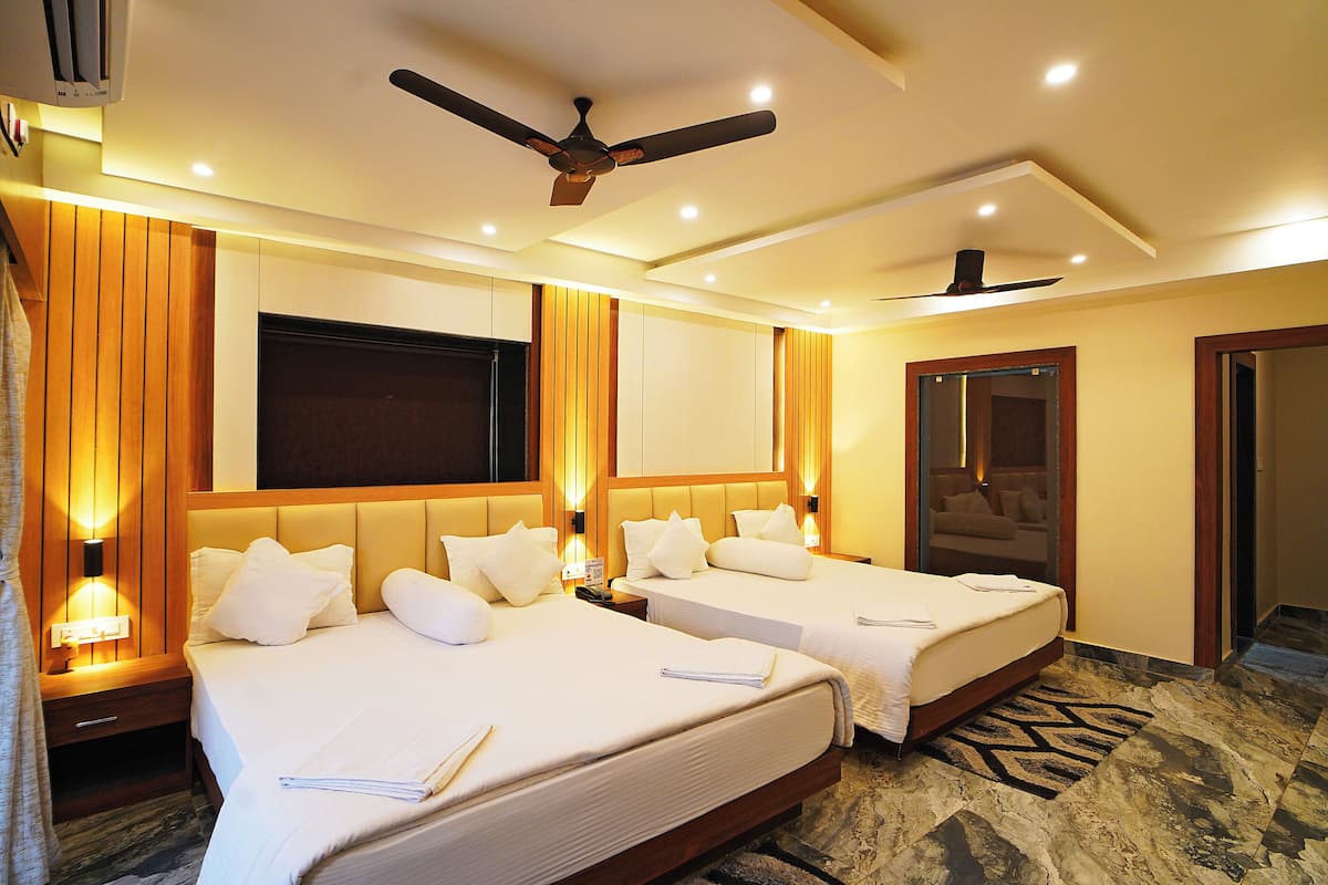 A hotel room with two beds, a ceiling fan, and a large TV screen.