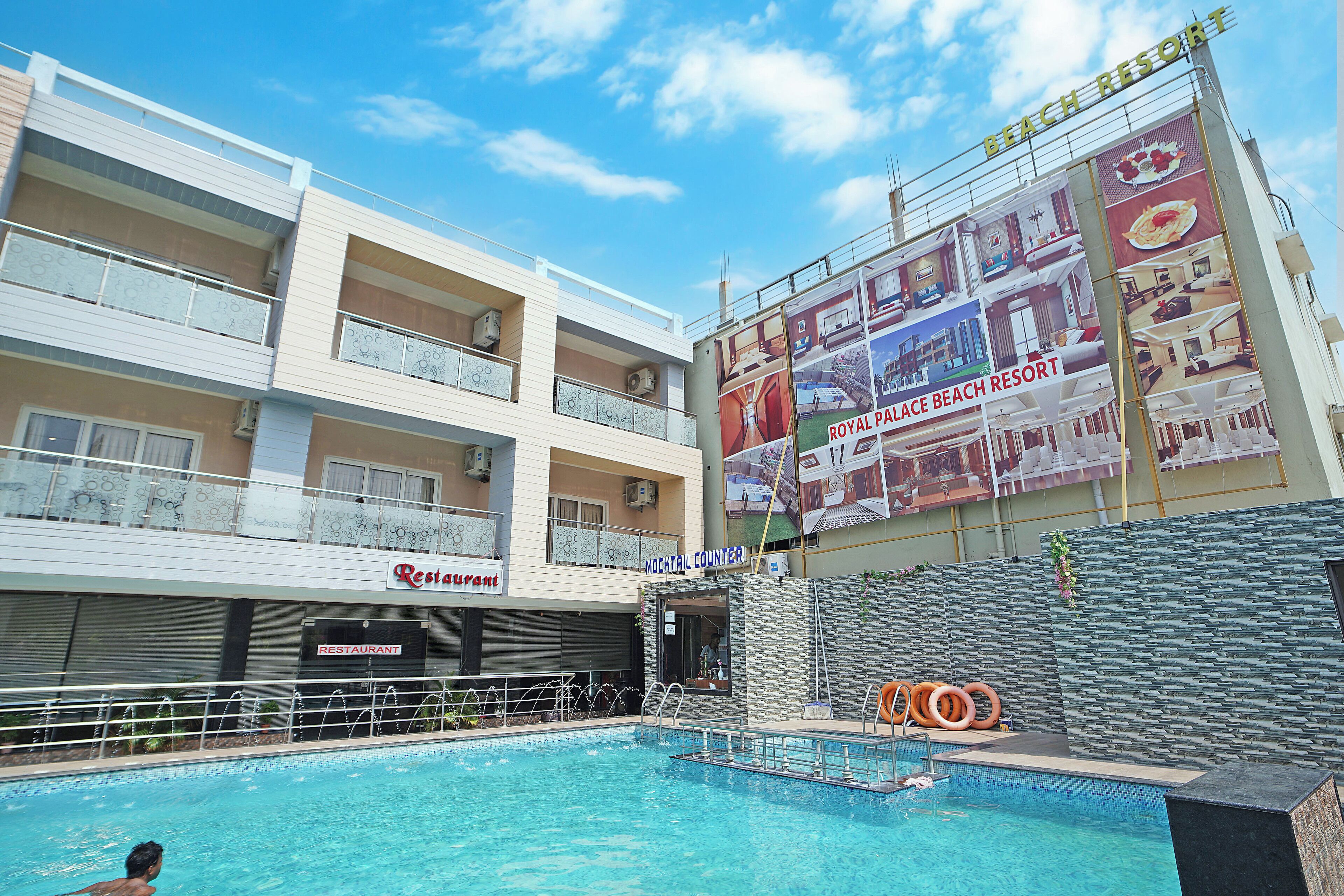 A hotel with a swimming pool, a restaurant, and a large billboard advertising the Royal Place Beach Resort.