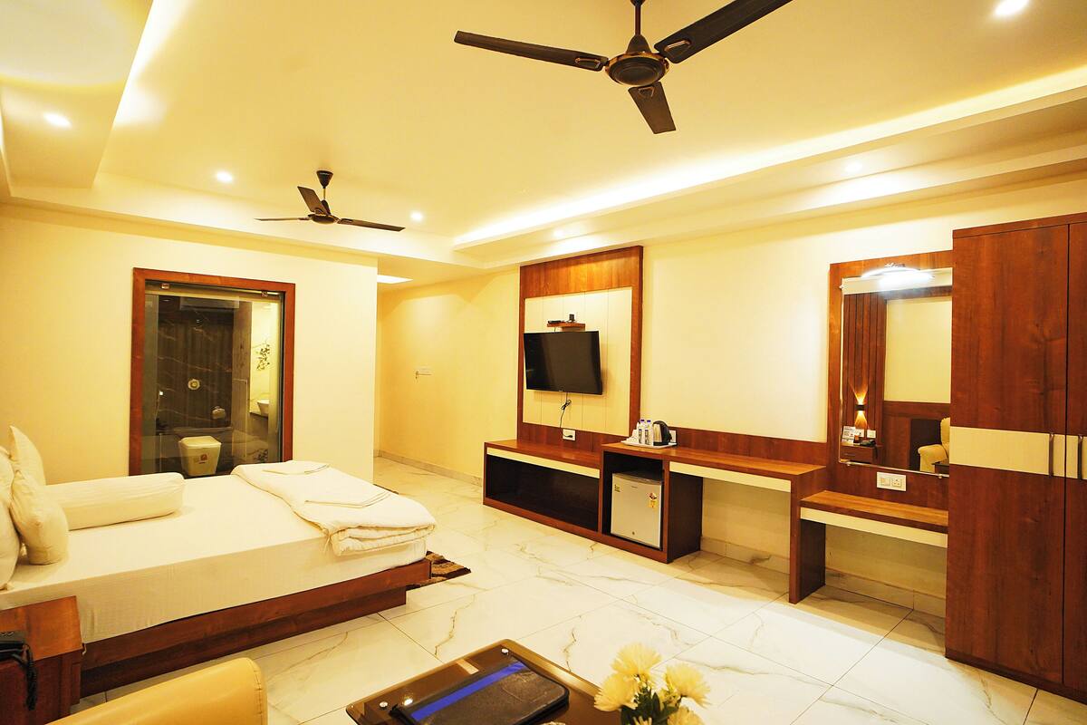 A hotel room with a bed, a desk, a television, a mirror, and a ceiling fan.