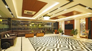 Eine moderne Lobby mit einem geometrisch gemusterten Boden, Ledersitzmöglichkeiten und einem großen Bildschirm.