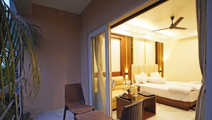 Ein Hotelzimmer mit Bett, einer Sitzecke mit Tisch und Stühlen sowie Blick ins Freie.