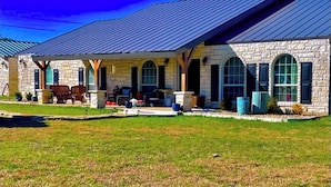 A stone building with a covered patio, large windows, and a sloped metal roof. - Stillhouse Lake Fishing Retreat -Cedar Creek Ranch, 10 Acres + Boat Parking (Salado)
