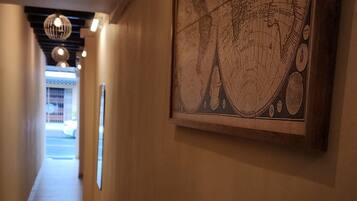 A hallway with a large map on the wall, a tiled floor, and hanging spherical lights.