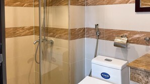 Une salle de bain moderne avec une douche à parois de verre, des toilettes blanches et un mur recouvert de carreaux de marbre.