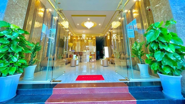 L’entrée d’un hôtel, avec un tapis rouge, des portes en verre et des plantes en pot.