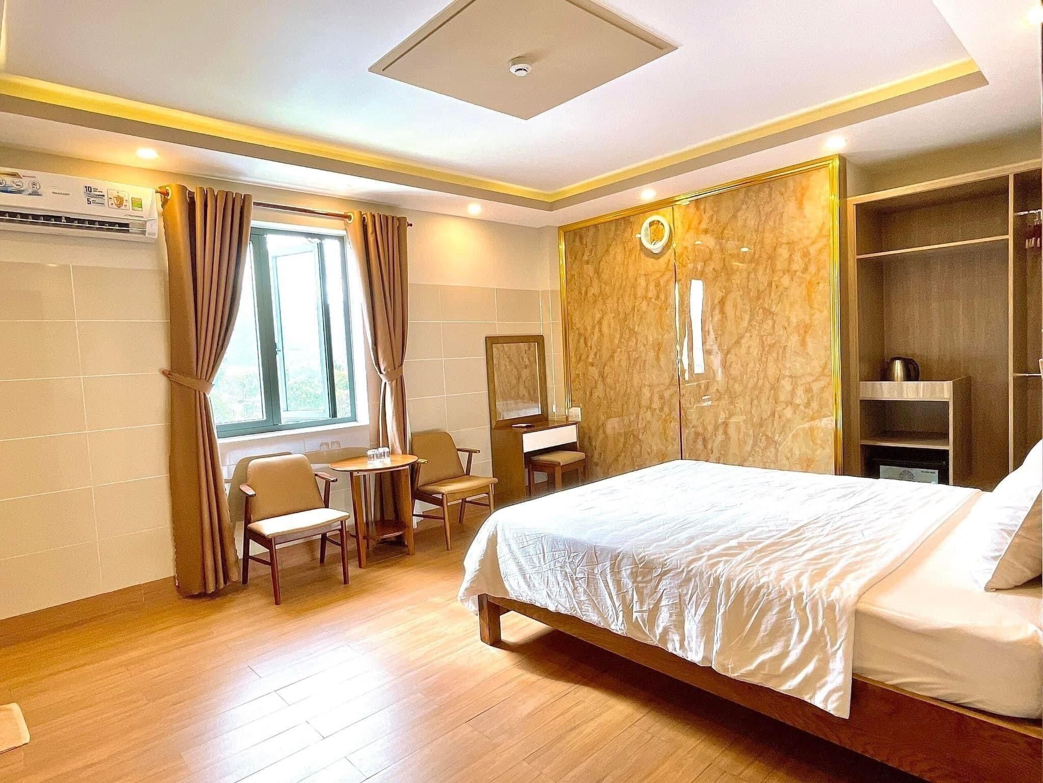 A hotel room with a bed, a desk, a chair, a wardrobe, and a window with curtains.