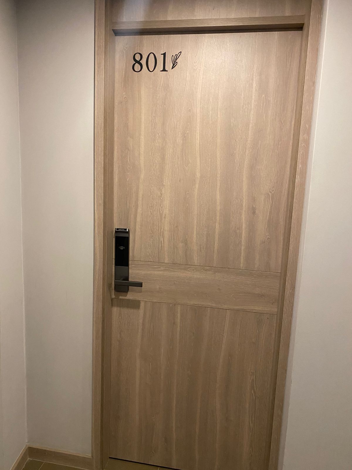 Une porte en bois portant le numéro 801 et un petit symbole représentant une feuille.