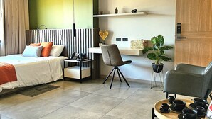 A modern hotel room with a bed, a seating area with a table and chairs, a small plant, and a wooden cabinet. - LINVING 35 8TH FLOOR VIP (Medellín)