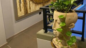 A hallway with a large wall art of golden wings, a potted plant in a sculptural pot, and a staircase with a railing. - LINVING 35 8TH FLOOR VIP (Medellín)