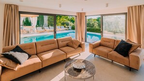 A modern living room with two beige sofas, a glass coffee table, and a view of an outdoor swimming pool. - Beautiful home in Privlaka with sauna (Privlaka)