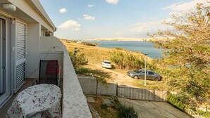 Ein Balkon mit Meerblick, ein geparktes Auto und ein Tisch mit Blumenmuster-Tischdecke.