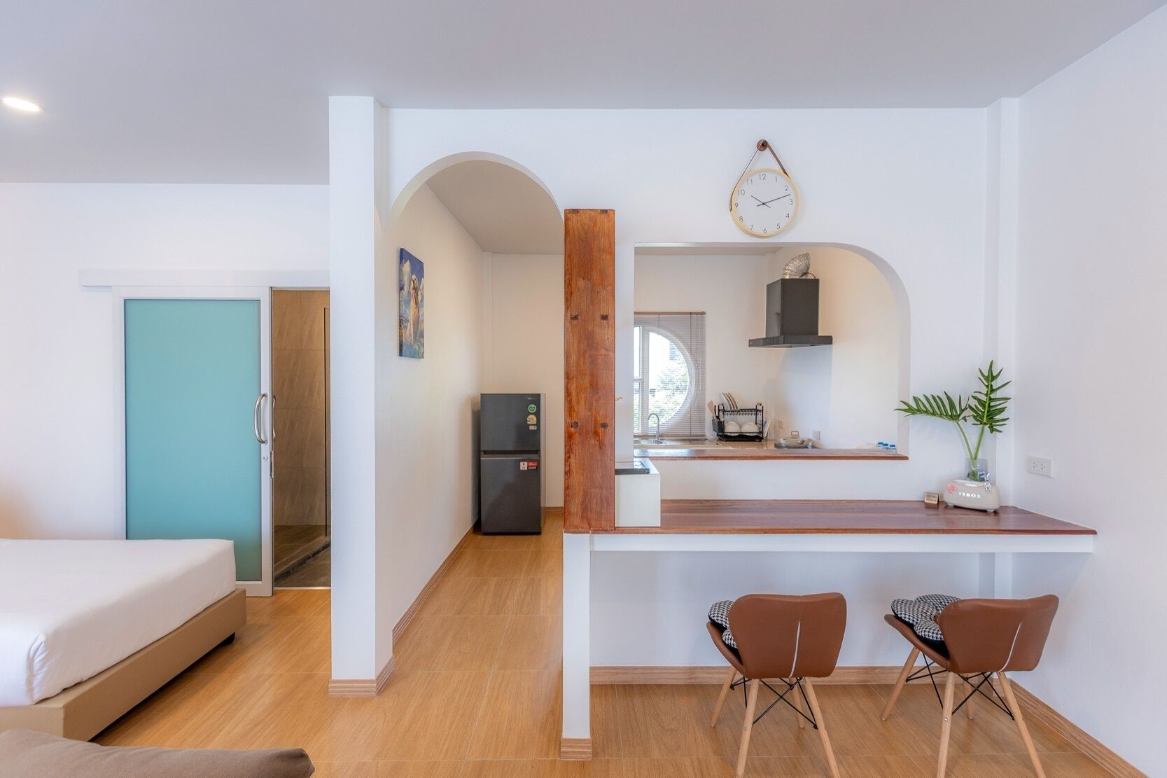 A compact living space with a kitchenette, a dining area with two chairs, a bed, and a door leading to another room.