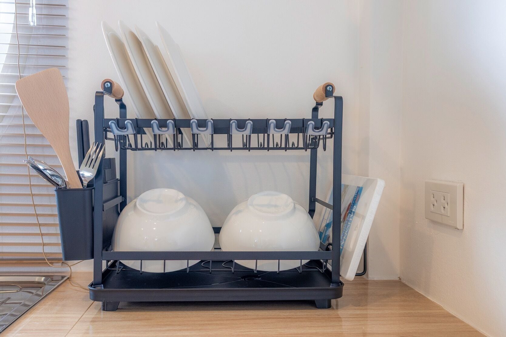 A kitchen with a utensil holder and two white pots on a black countertop.