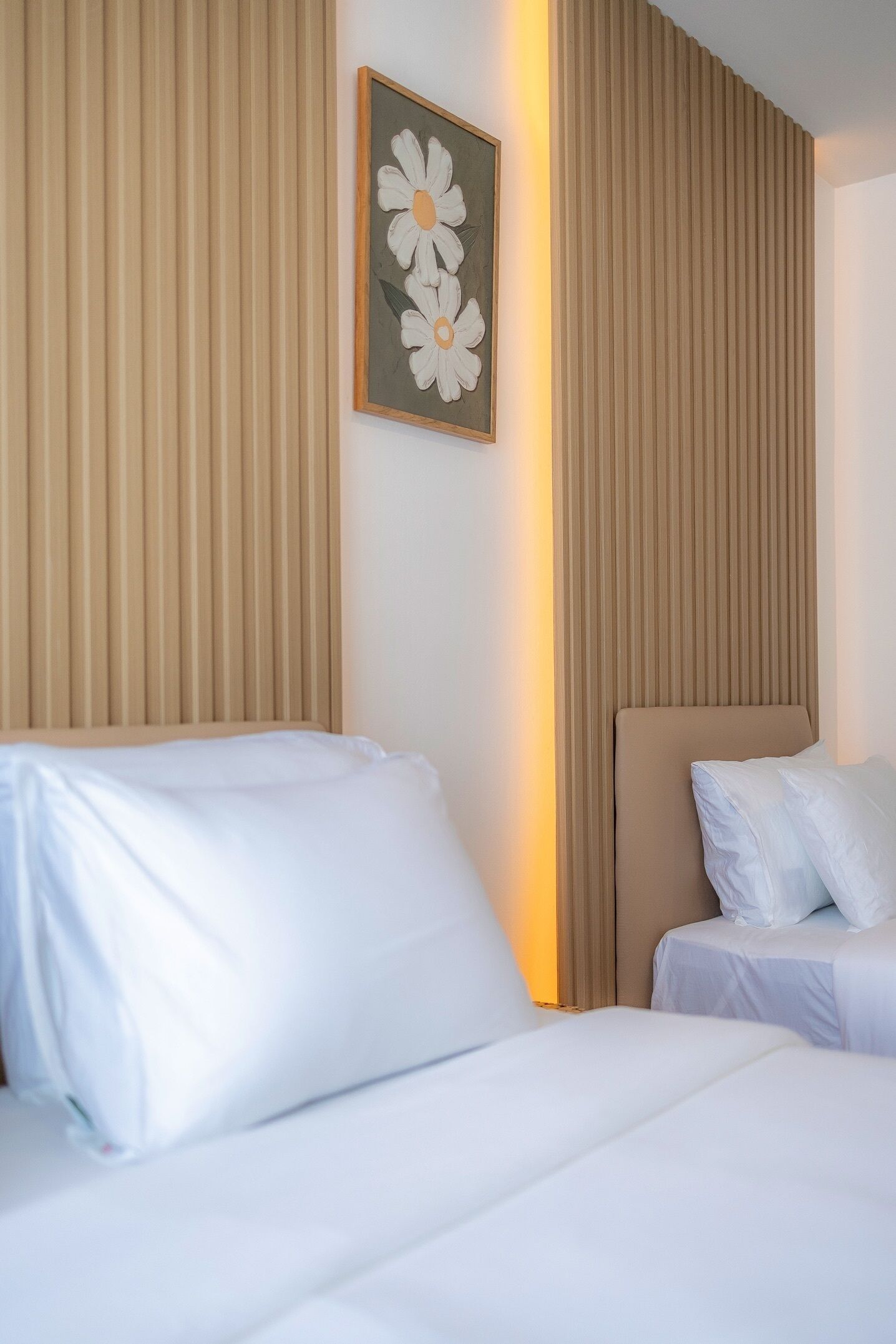 Ein Hotelzimmer mit zwei Betten, beigen Kopfteilen und einem an der Wand hängenden Blumenbild.