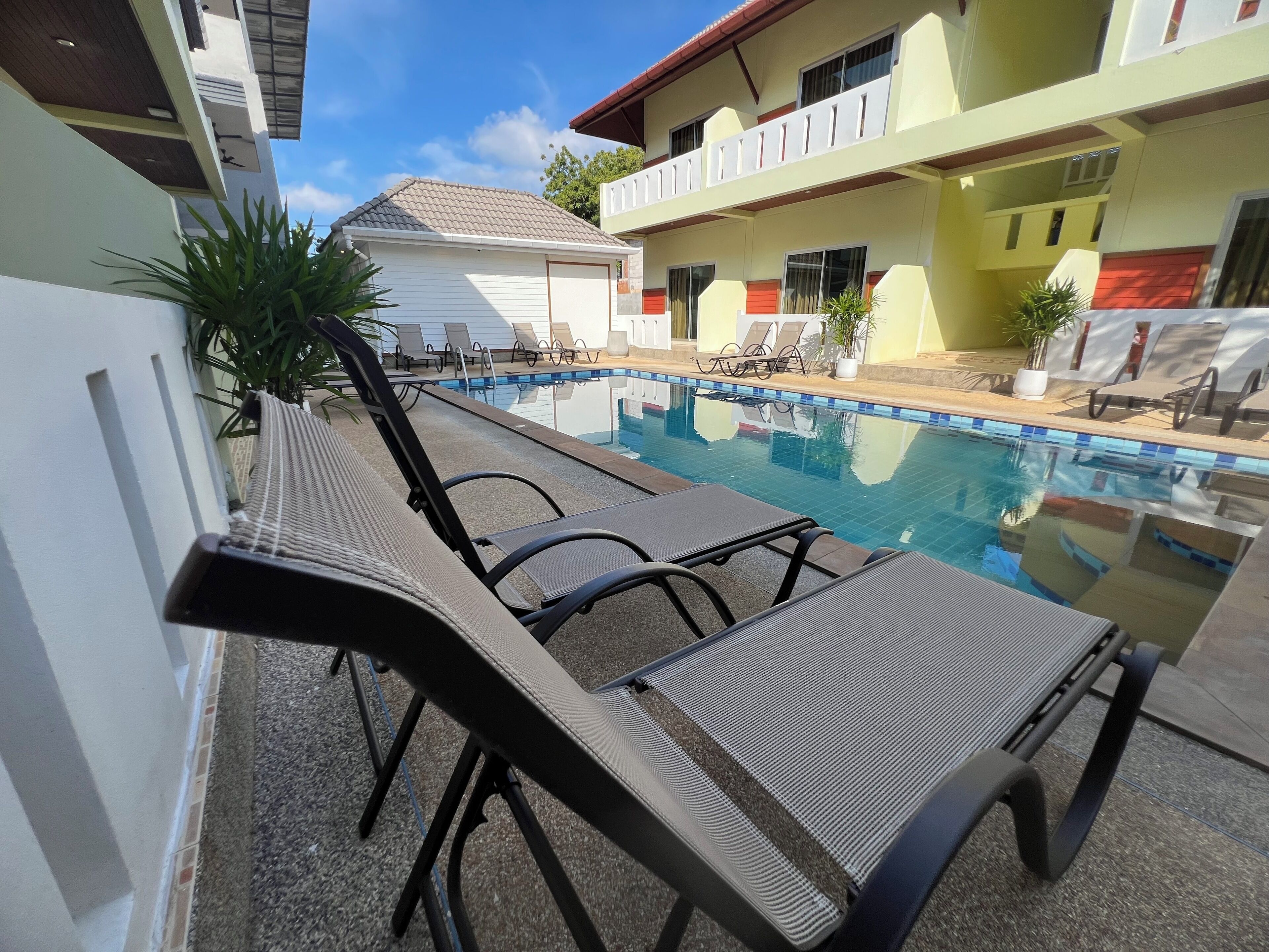 A swimming pool with lounge chairs and a building with balconies in the background.