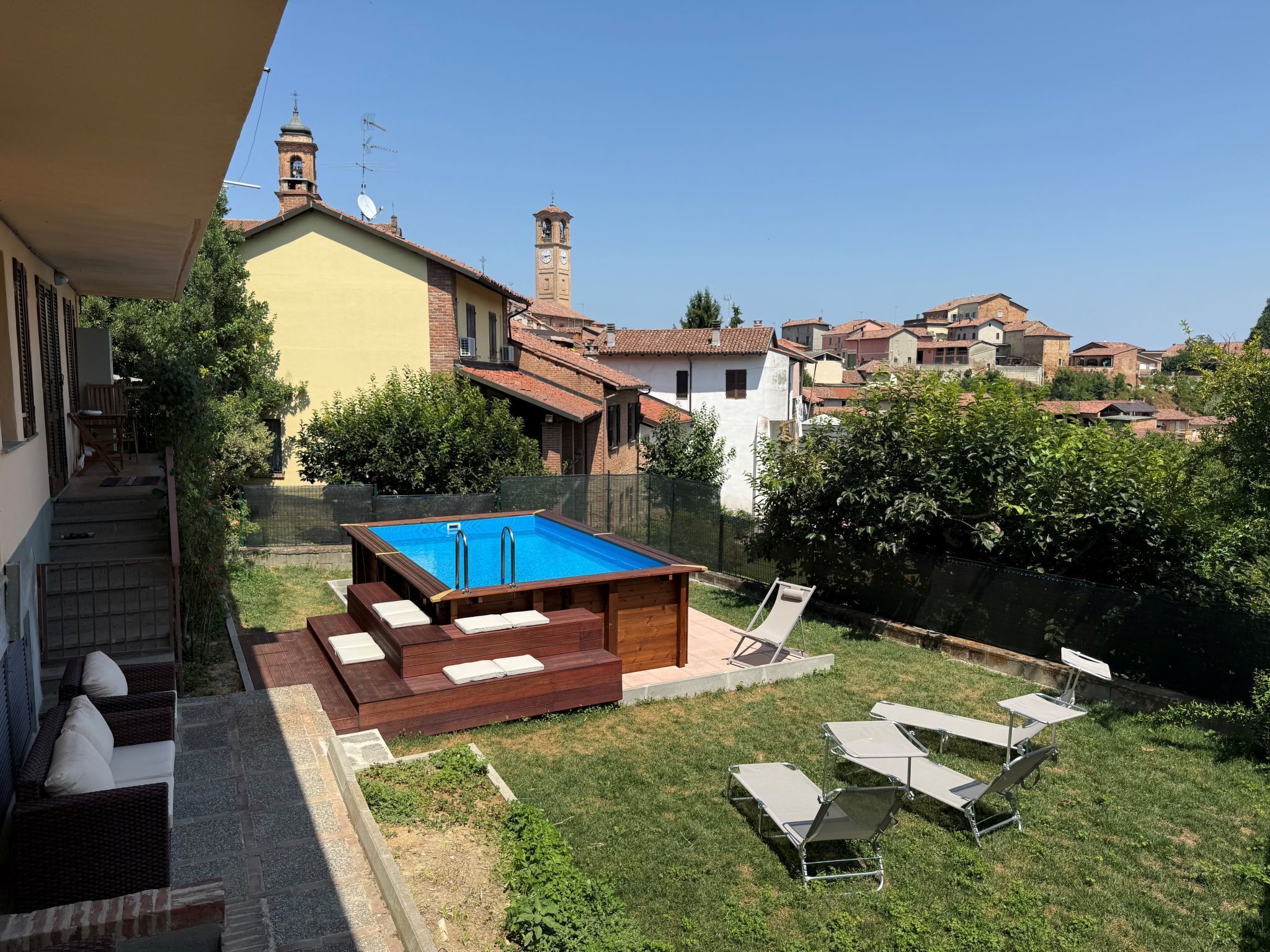 Zona residencial con piscina, sillas de descanso y una escalera que conduce a una casa.