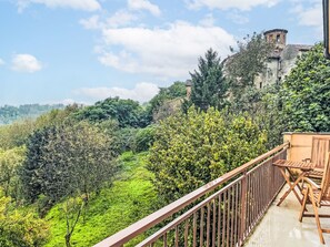A balcony with a view of a lush green landscape and a historic building in the background. - Il Borghetto di Castagnole by Interhome (Castagnole Monferrato)