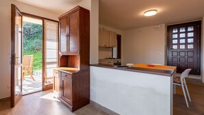A modern kitchen with wooden cabinets, a central island, and a dining area with a chair. - Il Borghetto di Castagnole by Interhome (Castagnole Monferrato)