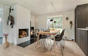 A modern dining area with a fireplace, a guitar, and a view of the outdoors. - 3 bedroom cozy home in Glesborg (Glesborg)