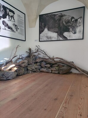 Ein Zimmer mit Holzboden, einer Steinsäule und zwei gerahmten Tierbildern.