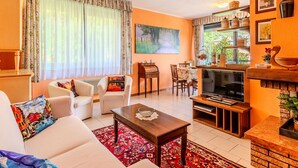 Un salón con sofá, mesa de centro, televisor y zona de comedor con sillas y una mesa.