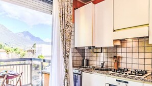 Cocina compacta con estufa a gas, horno y vista a las montañas desde la ventana.