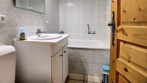 A bathroom with a sink, mirror, and bathtub. - Clos 22 - appartement - 10 pers - proche centre (Les Gets)