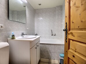 Une salle de bain avec un lavabo, un miroir et une baignoire.