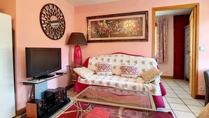 A living room with a sofa, a TV, a red lamp, and a framed painting on the wall. - Clos 22 - appartement - 10 pers - proche centre (Les Gets)
