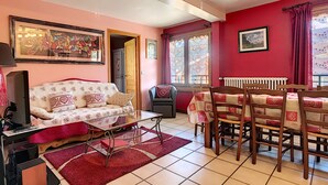 A living room with a sofa, TV, and dining table with chairs. - Clos 22 - appartement - 10 pers - proche centre (Les Gets)