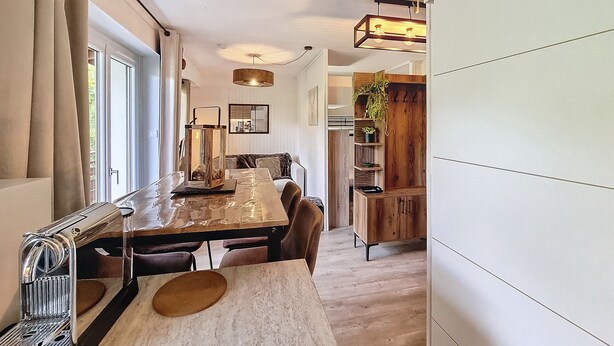 A modern dining area with a long table, chairs, and a coffee machine. - Virola - appartement - 4 pers - proche piste (Les Gets)