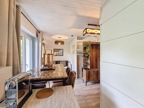 A modern dining area with a long table, chairs, and a coffee machine. - Virola - appartement - 4 pers - proche piste (Les Gets)