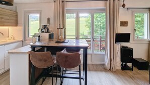 A kitchen with a dining area, a coffee machine, and a TV. - Virola - appartement - 4 pers - proche piste (Les Gets)