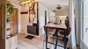 A modern kitchen with a central island, bar stools, and a decorative wall piece. - Virola - appartement - 4 pers - proche piste (Les Gets)