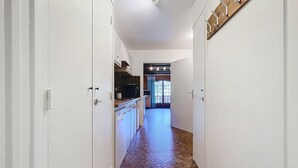 A hallway with white cabinets, a tiled floor, and a wooden door frame. - Hadès-appartement-4/5 pers- proche centre (Les Gets)