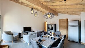 Una cocina moderna con comedor, vigas de madera en el techo y televisor integrado.