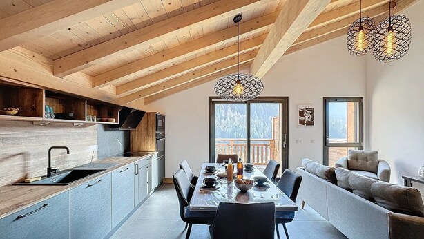 Una cocina moderna con vigas de madera, un rincón comedor con mesa y sillas, y un sofá.