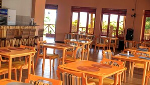 Un ristorante con tavoli e sedie di legno, ampie finestre e un'area riservata al buffet.