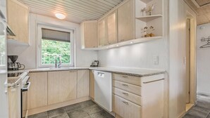 A modern kitchen with light wood cabinets, a window with blinds, a built-in dishwasher, and a countertop with a coffee maker. - Gorgeous home in Hemmet with WiFi (Hemmet)