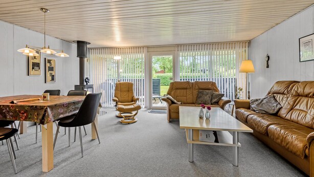 A spacious living area with a dining table, leather sofa, and a large window with blinds. - Gorgeous home in Hemmet with WiFi (Hemmet)