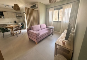 Una sala de estar moderna con un sofá, una mesa de comedor y una cocina al fondo.
