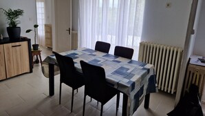 A dining area with a table, chairs, a potted plant, a radiator, and a clock on the wall. - Green holidays in the countryside (La Machine)