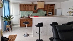 A kitchen with wooden cabinets, a white countertop, a microwave, and a red mat on the floor. - Green holidays in the countryside (La Machine)