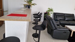 A modern kitchen with a bar area, a black leather sofa, and a dining table. - Green holidays in the countryside (La Machine)