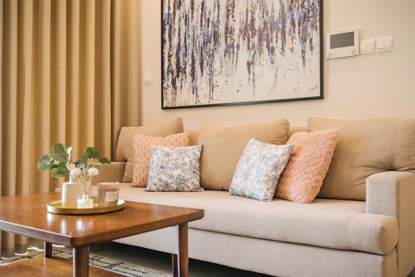 A living room with a beige sofa, a wooden coffee table, and a painting on the wall.