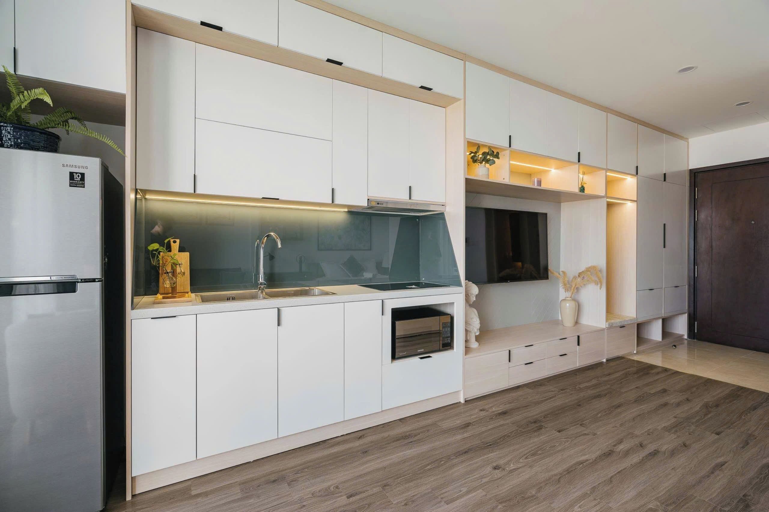 A modern kitchen with white cabinetry, a built-in oven, and a stainless steel refrigerator.