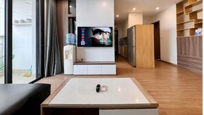 A modern living room with a TV, a water dispenser, and a ceiling fan.