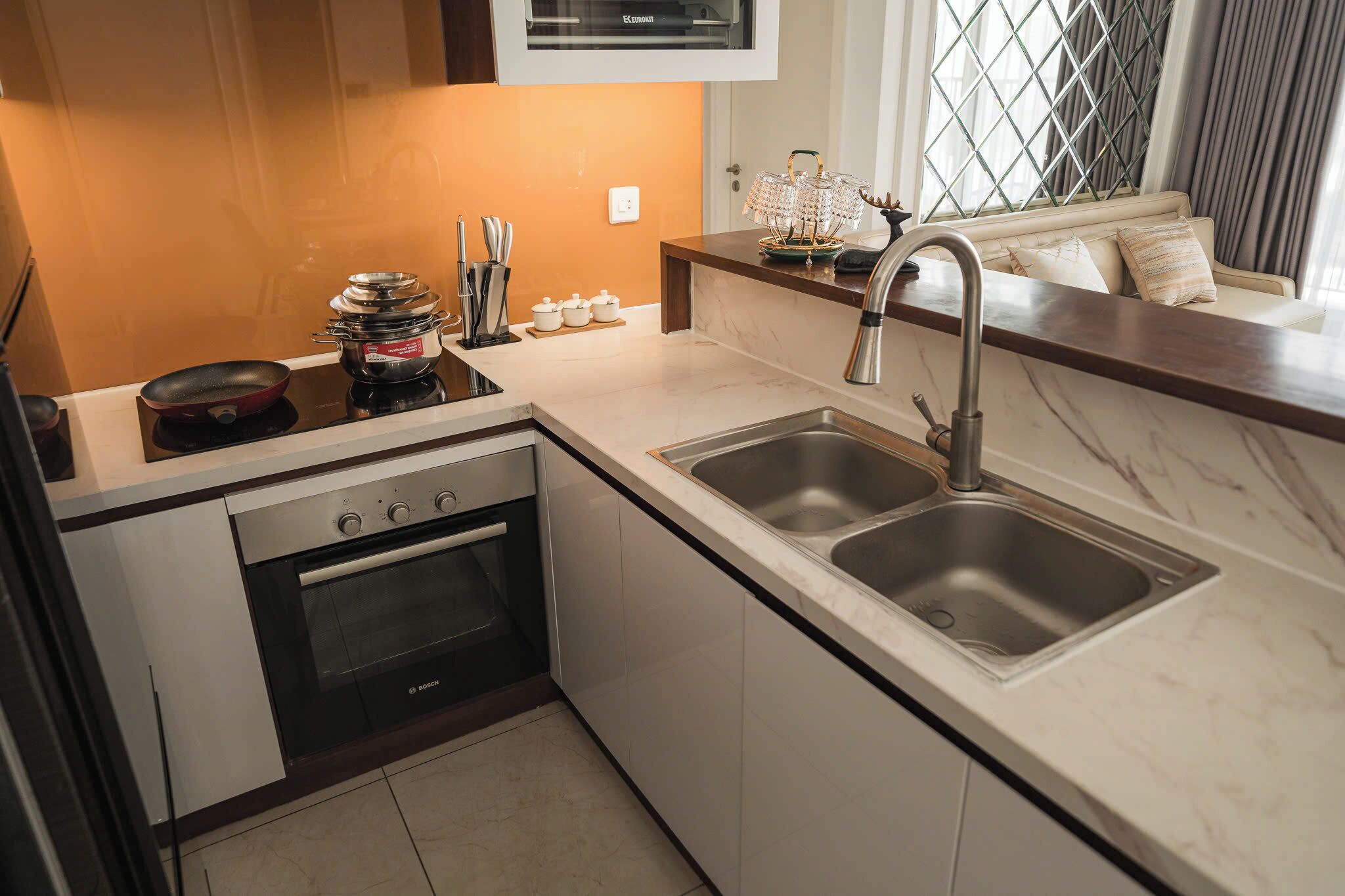 A modern kitchen with a built-in oven, a double sink, and a countertop with kitchen utensils.
